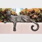 Bronze sculpture of a panther laying on a wall. 