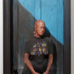 Sculpture of a woman in black t-shirt in front of a door.
